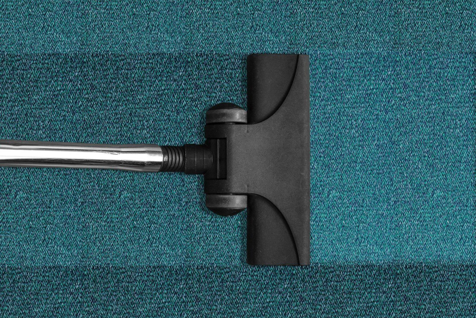 Vacuum cleaner cleaning a dark green carpet