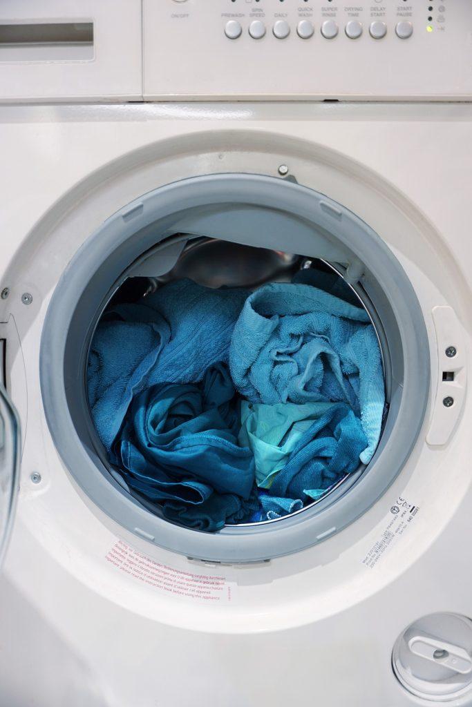 Photo of open washing machine with blue clothing inside