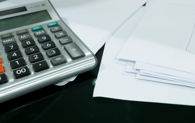 A calculator and stack of letters