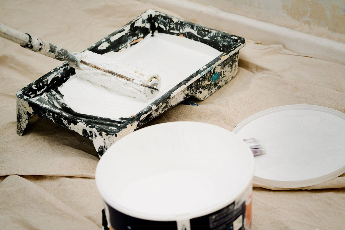 A white pot of matte paint and roller tray