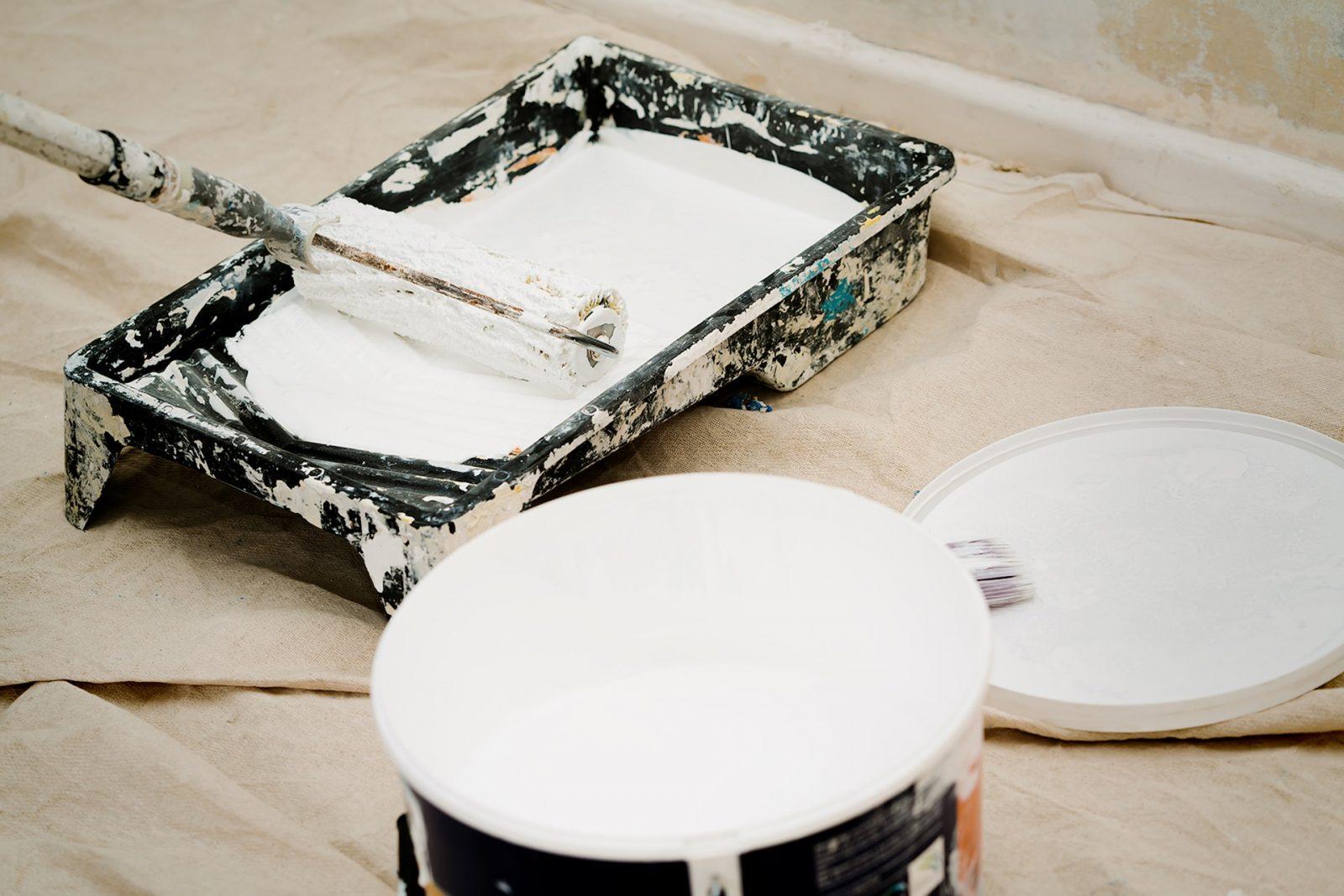 A white pot of matte paint and roller tray